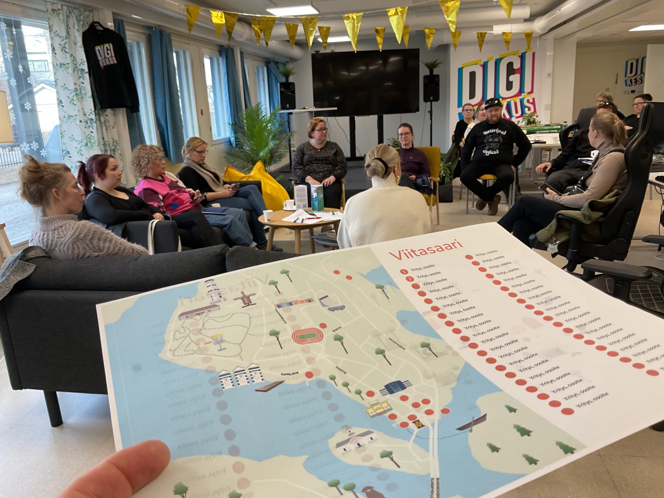 Ihmisiä Digikeskuksella työpajassa ja luonnos palvelukarttakuvasta ihmisen kädessä